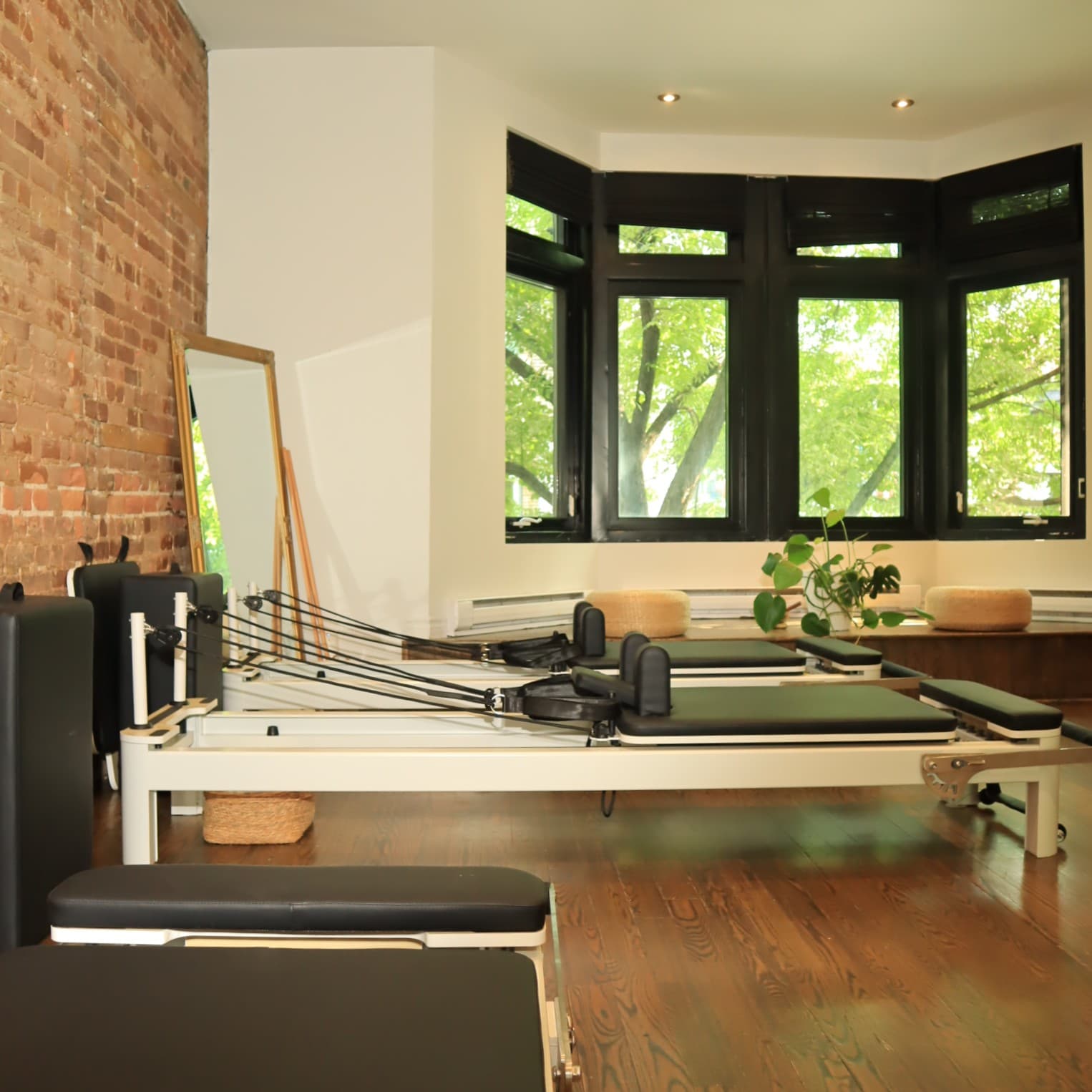 Reformer Pilates room at Stay at Home Studio with exposed brick and bay windows